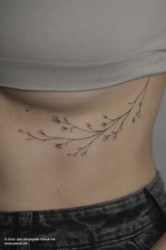 a woman's stomach with small flowers on the side, showing her lower back