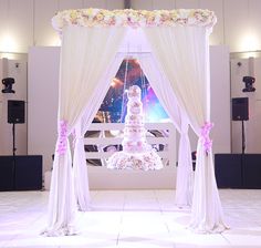 a wedding ceremony setup with white drapes and pink flowers