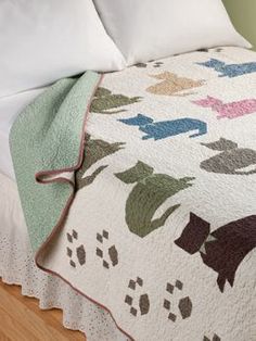 a bed with a white bedspread covered in cats and paw prints on it