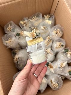 a hand is holding up a small cupcake in a cardboard box filled with white frosting