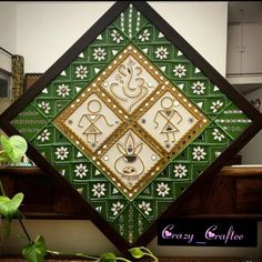 a green and white decorative wall hanging on the side of a wooden window sill