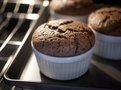 three muffins sitting on top of an oven in white dishes next to each other