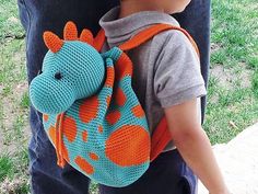 a young boy carrying a crocheted giraffe backpack