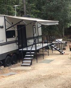 an rv parked on the side of a dirt road with stairs leading up to it