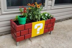 a planter made out of lego blocks with flowers in it and a question mark painted on the side