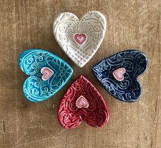 three heart shaped dishes sitting on top of a wooden table next to each other with hearts painted on them