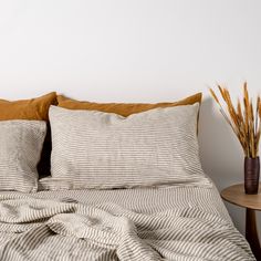 a bed with two pillows on top of it next to a night stand and table