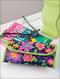 a pair of glasses sitting on top of a flowered case next to a green vase