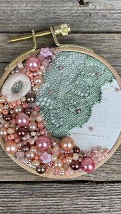 a close up of a embroidery on a wooden surface with beads and other things in it