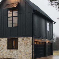 a black house with two garage doors and windows