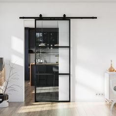 an open living room with white walls and wooden flooring, glass sliding doors leading to the kitchen