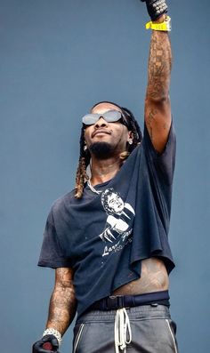 a man with dreadlocks and sunglasses on holding up his arm in the air