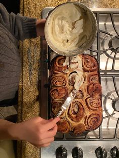 someone is spreading icing on top of a cinnamon roll in the oven with a spatula