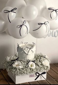 a white cake with black ribbon and balloons