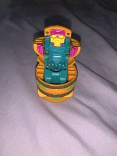 a plastic toy with a yellow and green vehicle inside it's case on a bed