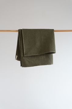 two folded green towels hanging on a clothes line with white walls in the back ground