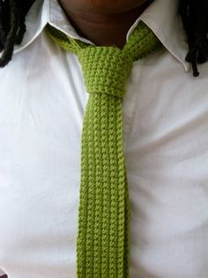 a person wearing a white shirt and a green crochet tie with dreadlocks