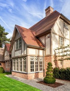 a large house that is in the middle of some grass and bushes, with a brick walkway leading up to it