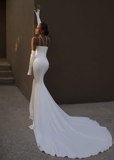 a woman in a white dress is posing for the camera with her hand on her head