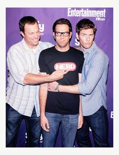 three men standing next to each other in front of a purple background