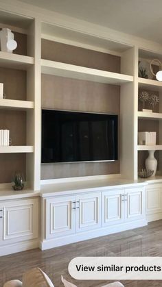 a living room with white bookcases and a flat screen tv mounted on the wall