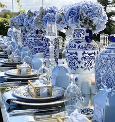 a table with blue and white plates, vases and napkins on it's sides