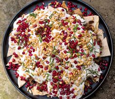 a black plate topped with nachos covered in cheese and cranberry sauce