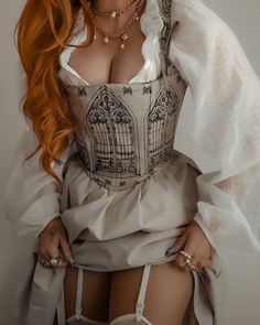 a woman with long red hair wearing a white dress and holding her hands on her hips