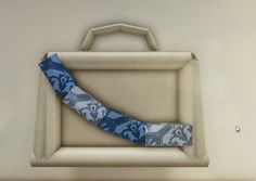 a blue and white tie sitting on top of a piece of luggage