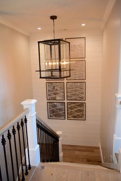 a stairway with pictures on the wall and chandelier hanging from it's ceiling