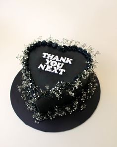 a black heart shaped cake with thank you next written on it