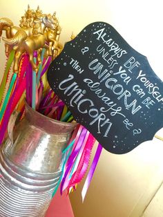 a metal vase filled with colorful streamers and a sign that says always do you know what the unicorns are doing