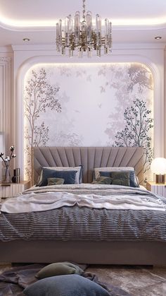 a large bed sitting under a chandelier next to a wall with trees on it