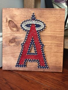 a wooden sign with beaded letters and an angel on the letter'a '