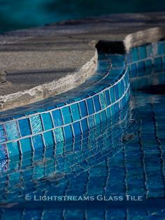 an empty swimming pool with blue tiles on the edge and water running down it's sides