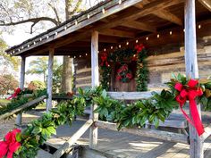 christmas wreaths on the porch of a log cabin decorated with greenery and lights