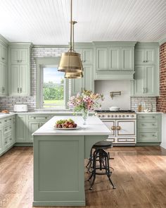 a large kitchen with green cabinets and white counter tops, along with an island in the middle