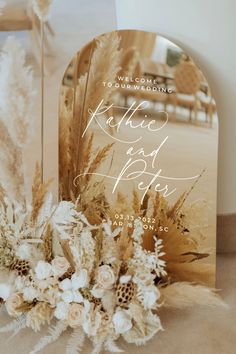 an image of a wedding card with flowers and feathers on the table next to it