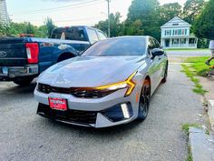 the front end of a gray car parked next to other cars