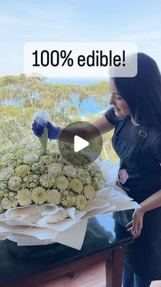 a woman is arranging flowers on a table with the words 100 % edible above it