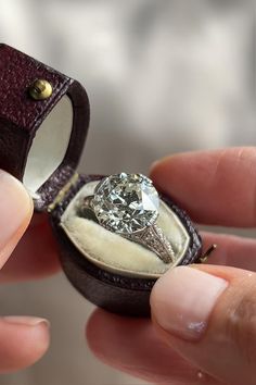 someone is holding a ring with a diamond in it and the inside of its box