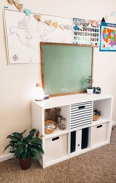 there is a chalkboard on the wall next to a shelf with bins and baskets