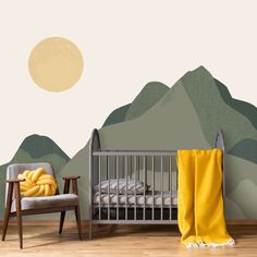 a baby crib in front of a mountain backdrop with a yellow blanket on it