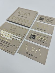 four business cards with gold foil on them, all in different shapes and sizes are shown