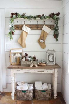 christmas stockings hung on the wall above a table with two baskets and other items in front of it