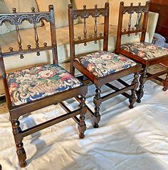 three wooden chairs sitting next to each other on top of a white cloth covered floor