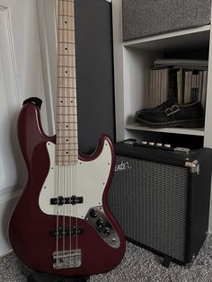 an electric bass guitar and amp sit on the floor next to a bookcase in a room