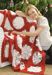 a woman sitting on the floor with a red and white crocheted blanket