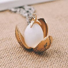 a necklace with an egg in it on top of a piece of cloth next to a chain