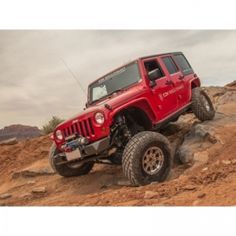 a red jeep parked on top of a rocky hill